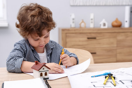 Choice of profession. Little kid with divider and engineering drawing at table indoorsの写真素材