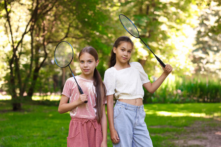 Portrait of smiling little girls with badminton rackets in parkの写真素材
