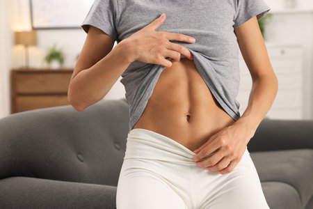 Woman with flat belly on sofa at home, closeupの写真素材