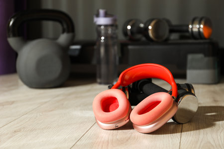 Wireless headphones and dumbbells on floor in gym. Space for textの写真素材