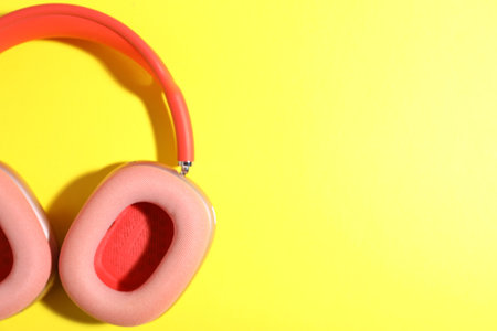 Pair of stylish pink headphones on yellow background, top view. Space for textの写真素材