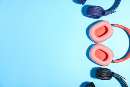 Different stylish headphones on light blue background, flat lay. Space for textの写真素材