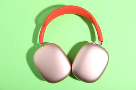 Pair of stylish pink headphones on light green background, top viewの写真素材