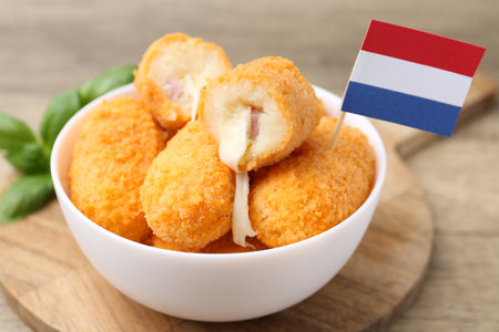 Delicious fried croquettes in bowl and basil on wooden table, closeupの写真素材