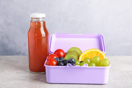 Open lunch box with delicious food and juice on gray table, closeupの写真素材