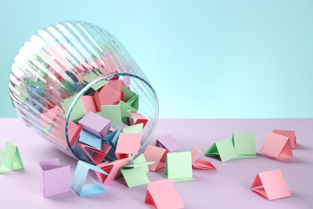 Bright paper pieces in glass jar on color background, closeup. Space for textの写真素材