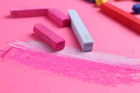 Many colorful chalk pastels on pink background, closeupの写真素材