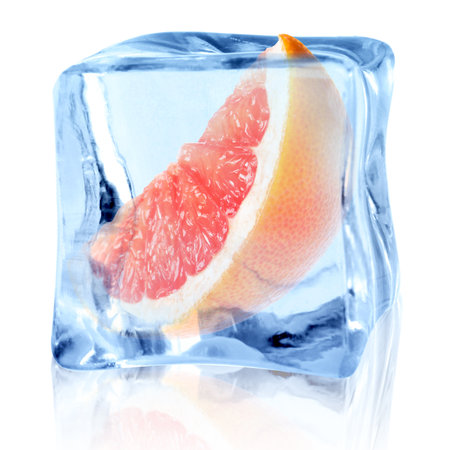 Piece of fresh grapefruit inside ice cube on white backgroundの写真素材