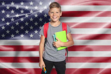 Little boy with backpack and stationery against flag of USA. Language schoolの写真素材