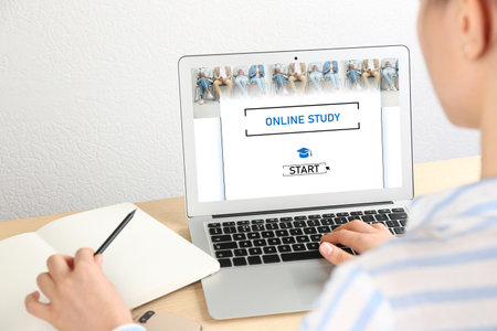 Online study. Woman using laptop for e-learning at desk, closeupの写真素材