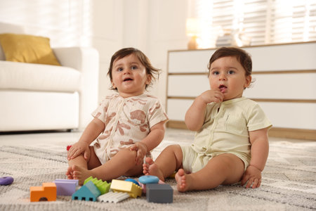 Cute little twin babies playing with toys on the floor at homeの写真素材