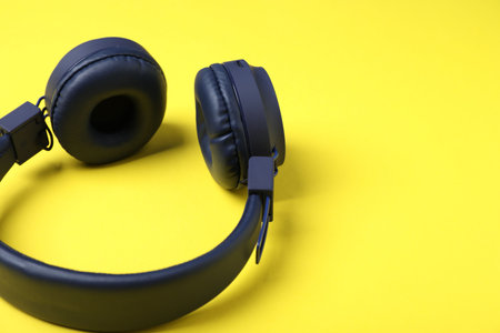 Pair of stylish headphones on yellow background, closeup. Space for textの写真素材