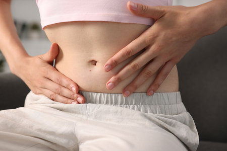 Woman with flat belly on sofa at home, closeup