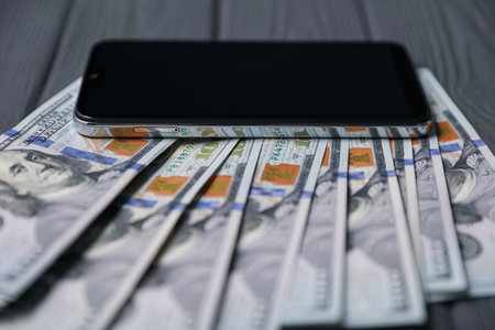 Smartphone and money on gray wooden table, closeupの写真素材