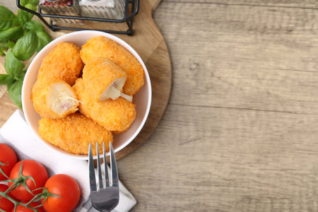 Delicious fried croquettes in bowl, tomatoes and spices on wooden table, flat lay. Space for textの写真素材