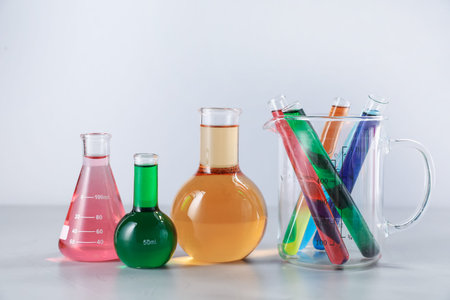 Different laboratory glassware with color liquids on light backgroundの写真素材