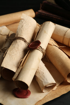 Many old rolled scrolls on black wooden table, closeupの写真素材