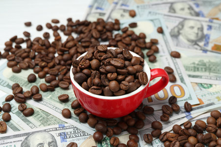 Roasted coffee beans, cup and dollar banknotes on white table, closeupの写真素材