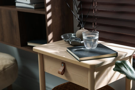 Wooden side table with glass of water, notebook and air reed diffuser indoorsの写真素材