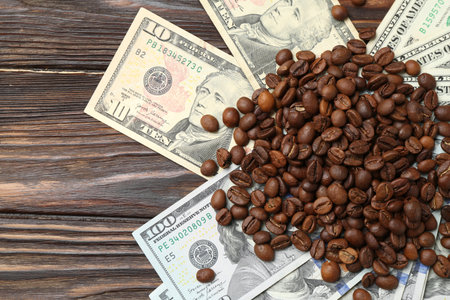 Pile of roasted coffee beans and dollar banknotes on wooden table, flat layの写真素材