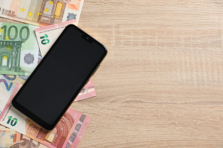 Smartphone and money on wooden table, flat lay. Space for textの写真素材