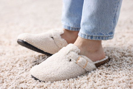 Woman in white slippers on soft carpet, closeup