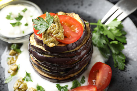 Tasty grilled eggplant slices with tomatoes, pesto and yoghurt on table, closeupの写真素材