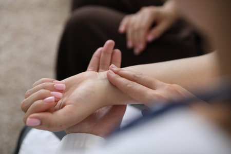 Doctor checking woman's pulse with fingers indoors, closeupの写真素材