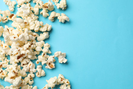 Tasty popcorn on light blue background, flat lay. Space for textの写真素材