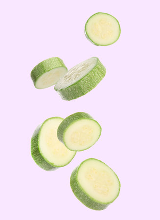 Fresh zucchini slices falling on light backgroundの写真素材