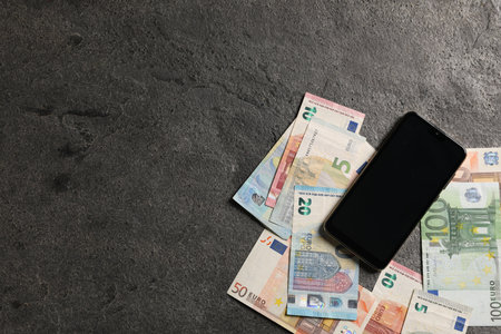 Smartphone and euro banknotes on gray table, flat lay. Space for textの写真素材