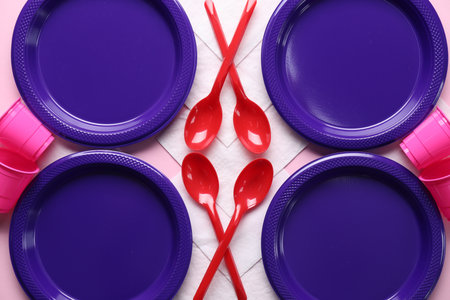 Set of disposable plastic tableware and paper napkins on pink background, flat lay. Space for textの写真素材
