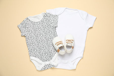 Stylish baby onesies and shoes on beige background, flat layの写真素材