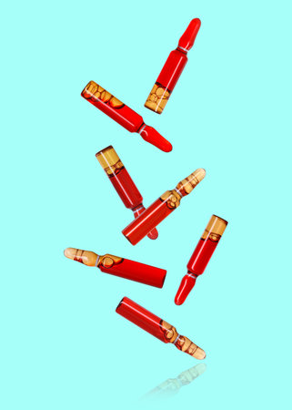 Many glass ampoules falling on turquoise backgroundの写真素材