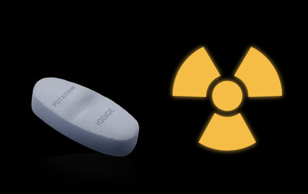 Potassium iodide pill and warning sign on black background. Iodine consumption during radioactive contaminationの写真素材