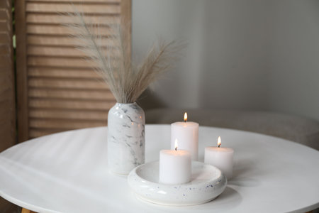 Burning candles on white table at home. Space for textの写真素材