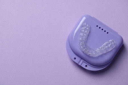 One clear aligner and retainer case on violet background, top view. Space for textの写真素材