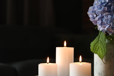 Burning candles and hydrangea flowers at home, closeup. Space for textの写真素材