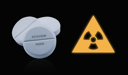 Potassium iodide pills and warning sign on black background. Iodine consumption during radioactive contaminationの写真素材