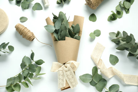 Florist. Eucalyptus branches, threads, ribbon and wrapping paper on white table, flat layの写真素材