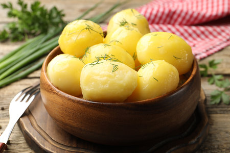 Tasty young boiled potatoes with dill served on wooden table, closeupの写真素材