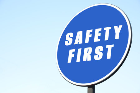 Safety First sign on pole against blue sky outdoors