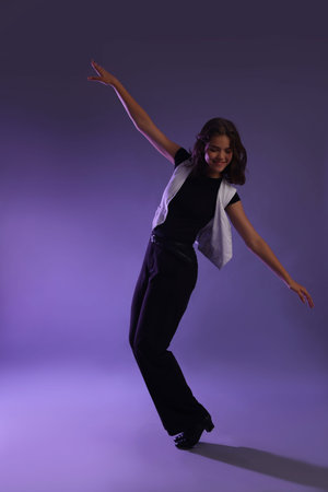 Teenage girl in tap shoes dancing on color background