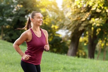 Athletic young woman in sportswear running outdoors, space for text