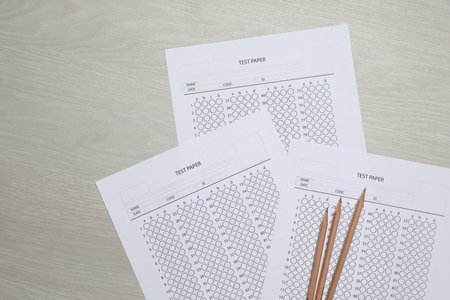 Answer sheets and pencils on wooden table, flat lay. Student passing exam