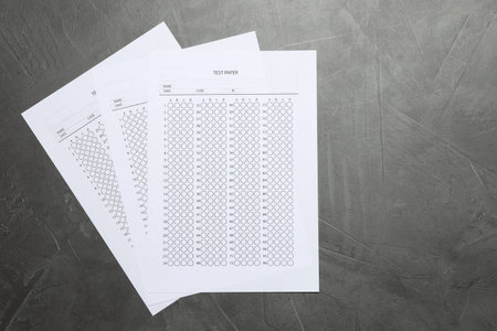 Answer sheets on gray textured table, flat lay. Student passing exam