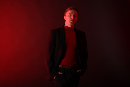 Portrait of handsome man wearing suit in neon lights against dark backgroundの写真素材
