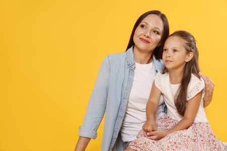 Lovely mother and daughter on yellow background. Space for textの写真素材