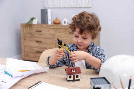Choice of profession. Little kid with divider pretending to be engineer at table indoorsの写真素材