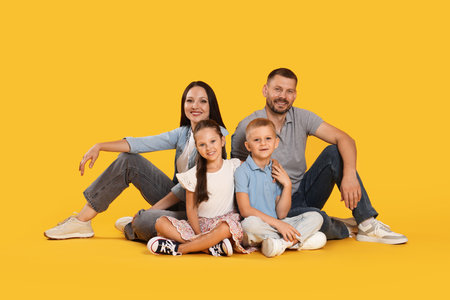 Lovely family posing together on yellow backgroundの写真素材